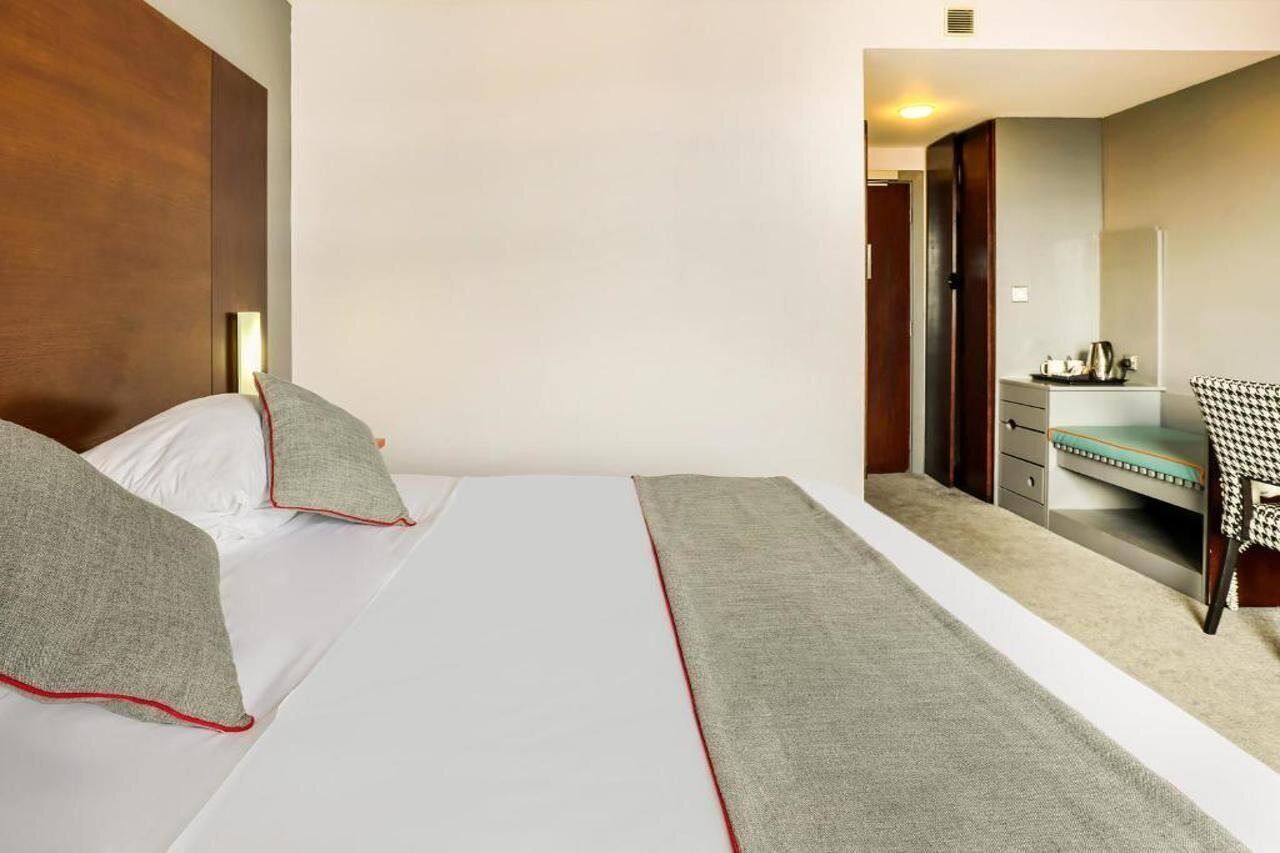 Una camera d'albergo con un letto, una scrivania, una sedia e uno specchio.