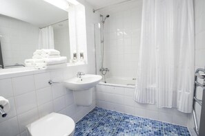 Un baño moderno con lavamanos, inodoro y ducha blancos.