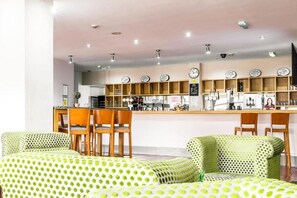 Un interior moderno con una zona de bar, sillas de madera y un sofá estampado.