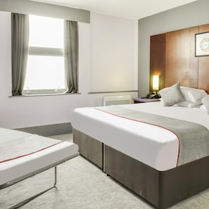 A hotel room with a bed, a bedside table with a lamp, a window with curtains, and a wall-mounted artwork. - Sheffield Metropolitan Hotel by Belvilla (Sheffield)