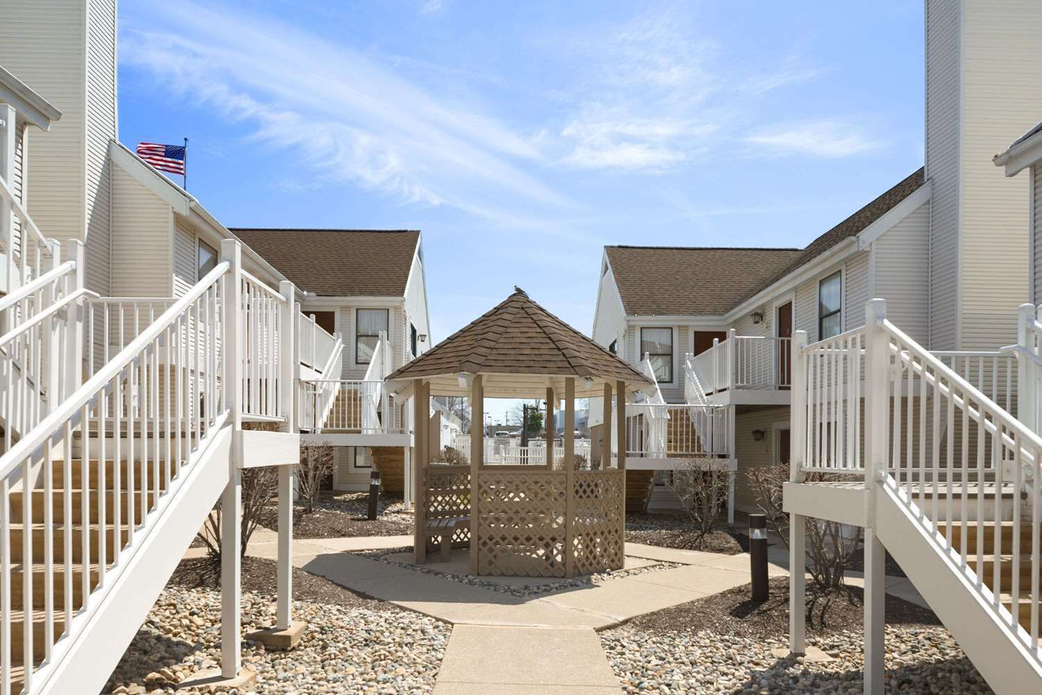 A residential building with a central gazebo, white railings, and a clear sky.