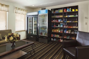 Een kamer met een bank, een salontafel, een boekenkast en twee koelkasten.