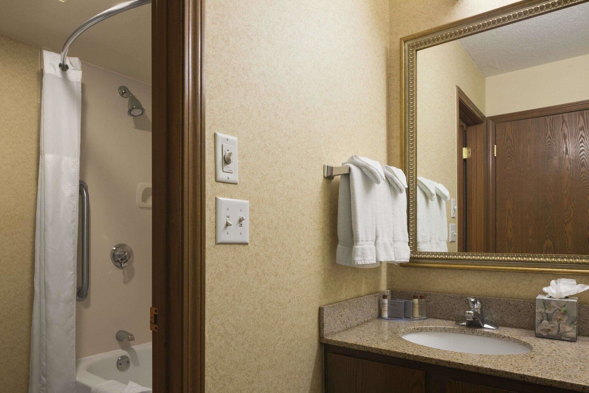 A bathroom with a shower, a sink, a mirror, and a towel rack.