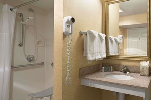 Une salle de bain équipée d’une douche, d’un sèche-cheveux, d’un porte-serviettes, d’un lavabo et d’un miroir.