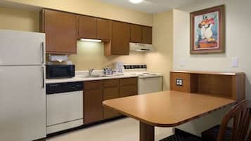 A compact kitchen with a refrigerator, microwave, stove, and sink.