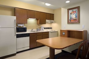 Una cocina compacta equipada con refrigerador, microondas, estufa y lavamanos.