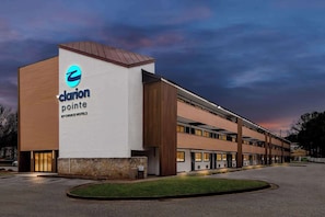 A hotel with a modern design, featuring a prominent logo on the facade, multiple floors, and a parking lot. - Clarion Pointe Kennesaw Town Center (Kennesaw)