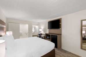 A hotel room with a bed, a desk, a television, a mirror, and a microwave. - Clarion Pointe Kennesaw Town Center (Kennesaw)