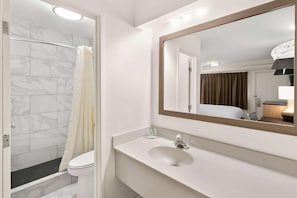 A bathroom with a shower, toilet, sink, and mirror. - Clarion Pointe Kennesaw Town Center (Kennesaw)
