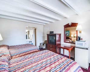 A hotel room with two beds, a television, a desk with a lamp, and a microwave. - Rodeway Inn Galax (Galax)