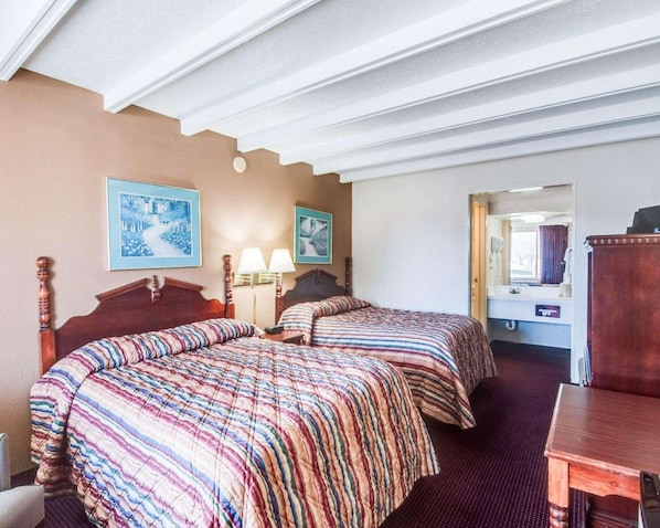 A hotel room with two beds, a wooden headboard, a small table, and a mirror. - Econo Lodge Galax, VA (Galax)