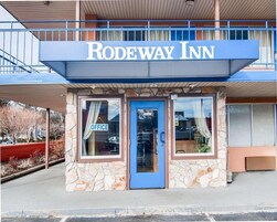 Un edificio con un cartel que dice 'RODEWAY INN' y una puerta azul con un letrero que indica 'OFICINA'.
