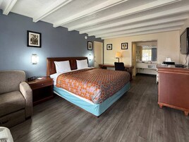 Una habitación de hotel con una cama, un escritorio, una silla y un televisor.