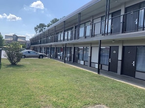 A multi-story motel with a flat facade, large windows, and a parking area with a single car. - Motel6 Tuscaloosa, AL University (Tuscaloosa)