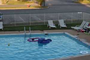 A swimming pool with lounge chairs and a fence.