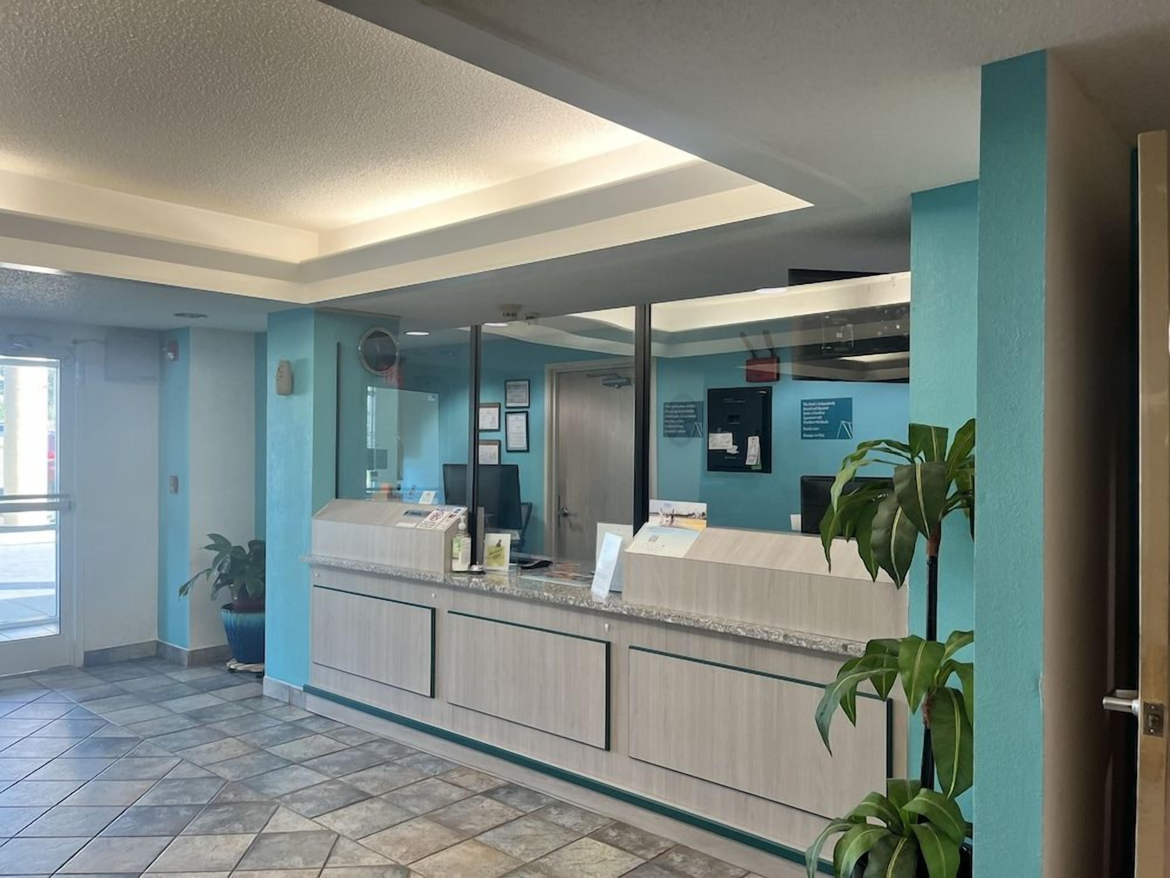 A reception area with a counter, a large mirror, and a door.