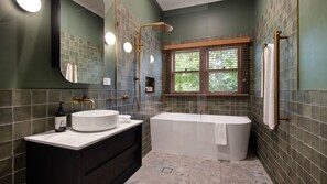 A modern bathroom with a freestanding bathtub, a large mirror, and a window with a view of trees. - Higgins House - Hepburn Springs (Hepburn Springs)