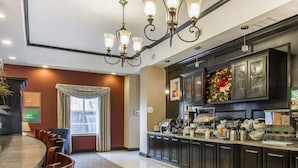 A hotel kitchen with a buffet setup, a dining area with a round table and chairs, and a chandelier. - Red Roof Inn and Suites Longview (Longview)
