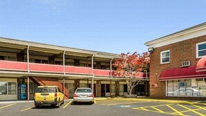 A parking lot with two cars, a building with a red awning, and a clear blue sky. - Econo Lodge Framingham (Framingham)