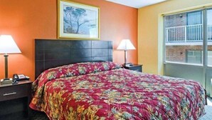 A hotel room with a bed, two bedside lamps, a telephone, a framed picture on the wall, and a window with a view of a building. - Econo Lodge Framingham (Framingham)