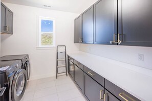 A laundry room with a washing machine, drying rack, and cabinets. - 12829 North Belaview Way (Daniel)