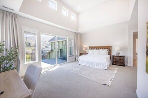 A spacious bedroom with a large bed, a desk, and a view of a balcony. - 12829 North Belaview Way (Daniel)