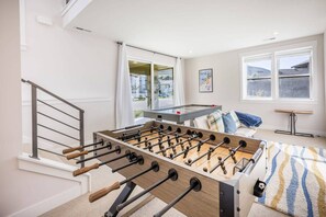 Ein Zimmer mit Kicker, einer Couch und einem Fenster mit Blick.