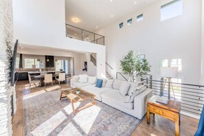 Amplia sala de estar con sofá, mesa de centro y una escalera que conduce a un nivel superior.
