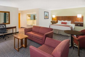 A hotel room with a bed, a desk, a sofa, a chair, and a small table. - Cedar City - UT (Cedar City)