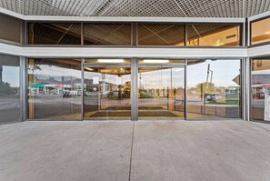 A modern building entrance with large glass doors, a concrete floor, and a view of a gas station in the background. - Cedar City - UT (Cedar City)