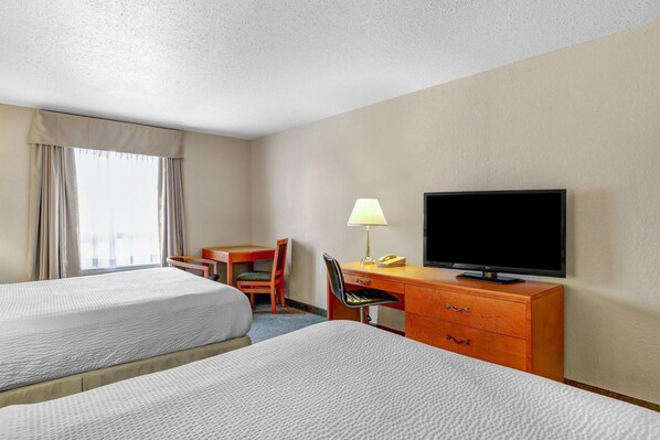 A hotel room with two beds, a desk with a lamp, a television, and a chair. - Days Inn Red Deer (Red Deer)