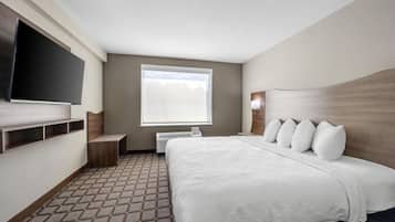 A hotel room with a large bed, a flat-screen TV mounted on the wall, a window with a view, and a patterned carpet.