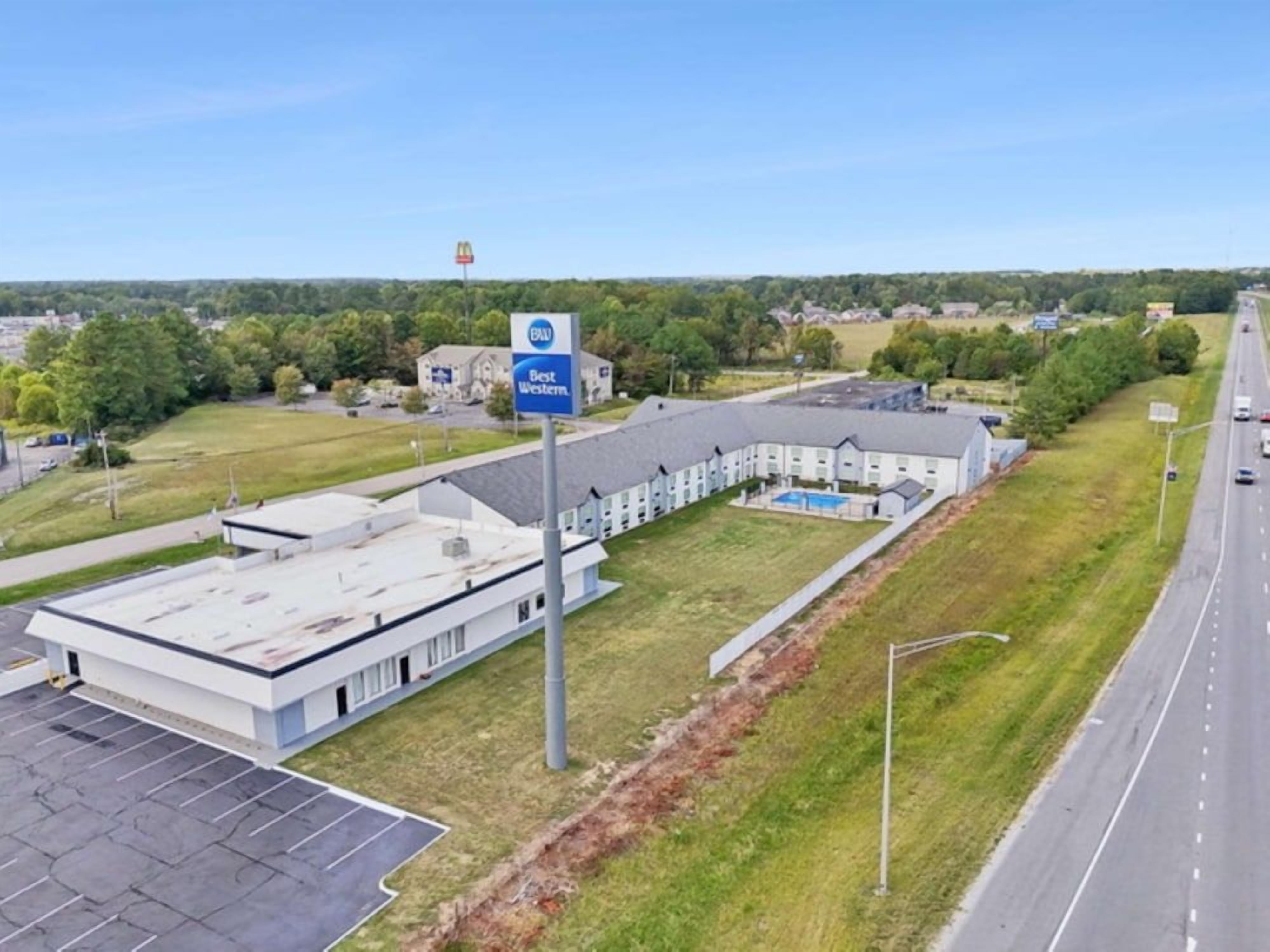 A commercial building with a parking lot, a swimming pool, and a sign for 'Best Western.'