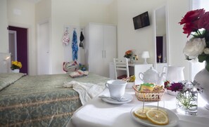 A hotel room with a bed, a table with breakfast items, a white wardrobe, and a mirror. - Hotel K2 (Ravenna)