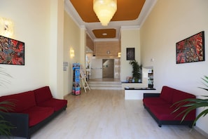 A hotel lobby with red sofas, a reception desk, and artwork on the walls. - Hotel K2 (Ravenna)