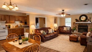 A spacious living area with a dining table, leather sofas, and a fireplace. - Buccaneer Bay Resort Cottage #56 (Sunrise Beach)