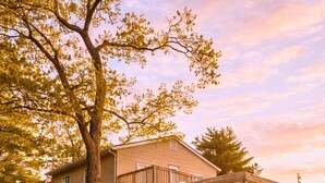 A two-story house with a porch, a staircase, and a view of a lake. - Buccaneer Bay Resort Cottage #56 (Sunrise Beach)