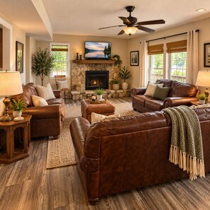 A living room with leather sofas, a fireplace, a television, and a ceiling fan. - Buccaneer Bay Resort Cottage #56 (Sunrise Beach)