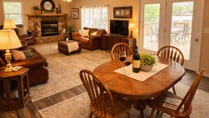 A spacious living room with a fireplace, a dining area, and a balcony with outdoor furniture. - Buccaneer Bay Resort Cottage #56 (Sunrise Beach)