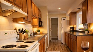 A kitchen with wooden cabinets, a stove, and a refrigerator. - Buccaneer Bay Resort Cottage #56 (Sunrise Beach)