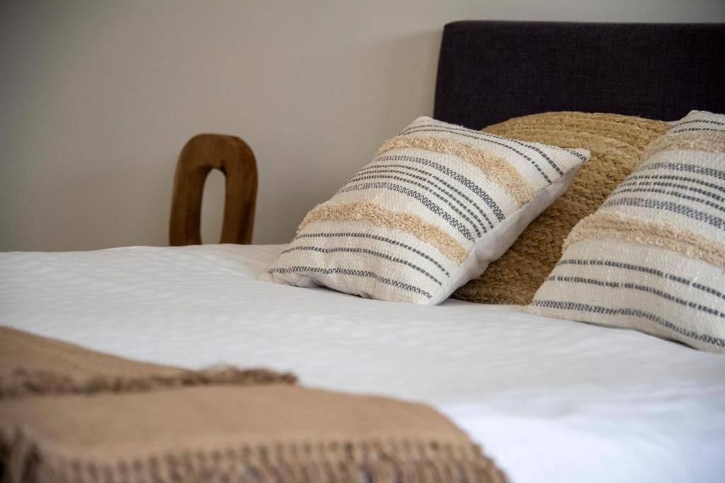 A bed with a headboard, two pillows with striped patterns, and a blanket.