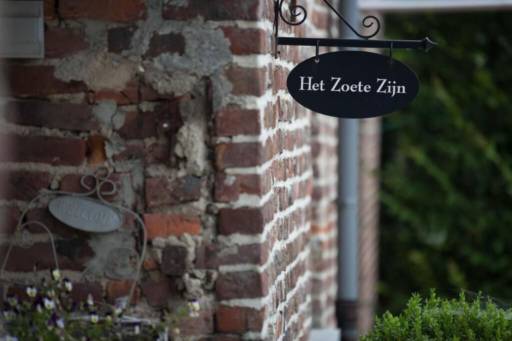 A brick wall with a sign that reads 'Het Zoete Zijn'.