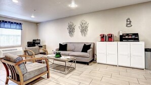Un salon comprenant un canapé, deux fauteuils, une table basse, un meuble de rangement et un élément décoratif mural.