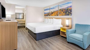 A hotel room with a bed, a desk with a lamp, a TV, a chair, and a painting on the wall. - Days Inn by Wyndham Leeds (Leeds)