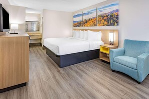 A hotel room with a bed, a desk with a lamp, a TV, a chair, and a painting on the wall. - Days Inn by Wyndham Leeds (Leeds)