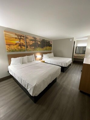 A hotel room with two beds, a nightstand, a desk, and a large painting on the wall. - Days Inn by Wyndham Leeds (Leeds)