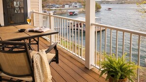 Une terrasse en bois avec une table et des chaises, d’où l’on a vue sur une étendue d’eau, avec des bateaux et des maisons en arrière-plan.