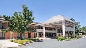 A modern hotel with a covered entrance, brick facade, and landscaped area. - Days Inn by Wyndham Perryville (Perryville)