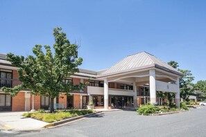 A modern building with a covered entrance, large windows, and a landscaped area with trees and shrubs. - Days Inn by Wyndham Perryville (Perryville)