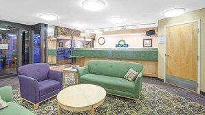 A lobby with a reception desk, a green sofa, a purple armchair, and a small table. - Days Inn by Wyndham Perryville (Perryville)